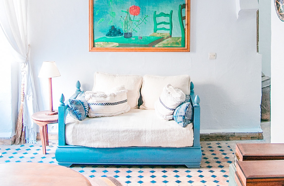 photo of a soft comfy couch with blue wooden railings in a ilaic room with lots of light